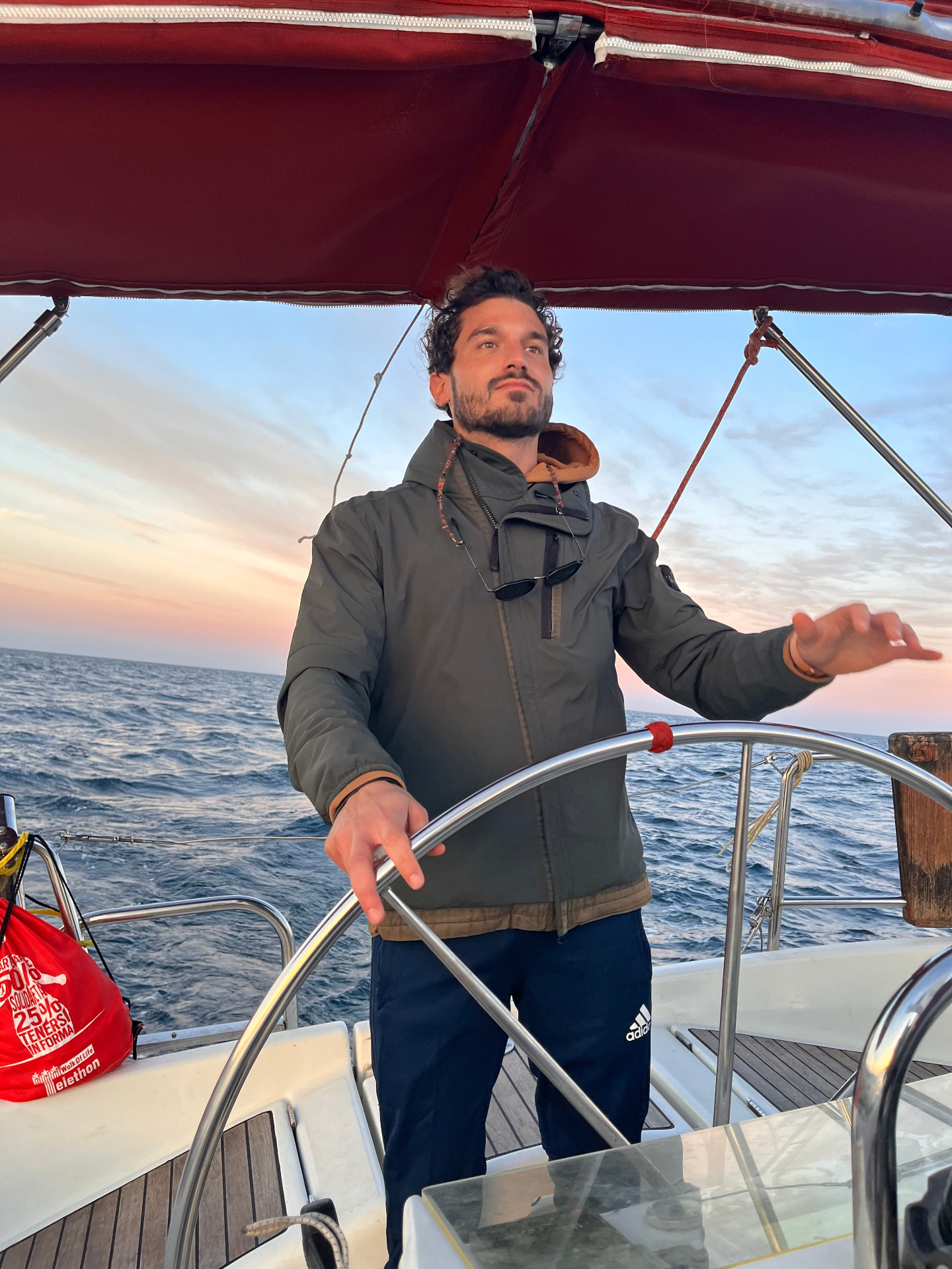 Gabriele Gianino, founder of SEAFLOW, at the helm of a sailboat at sunset